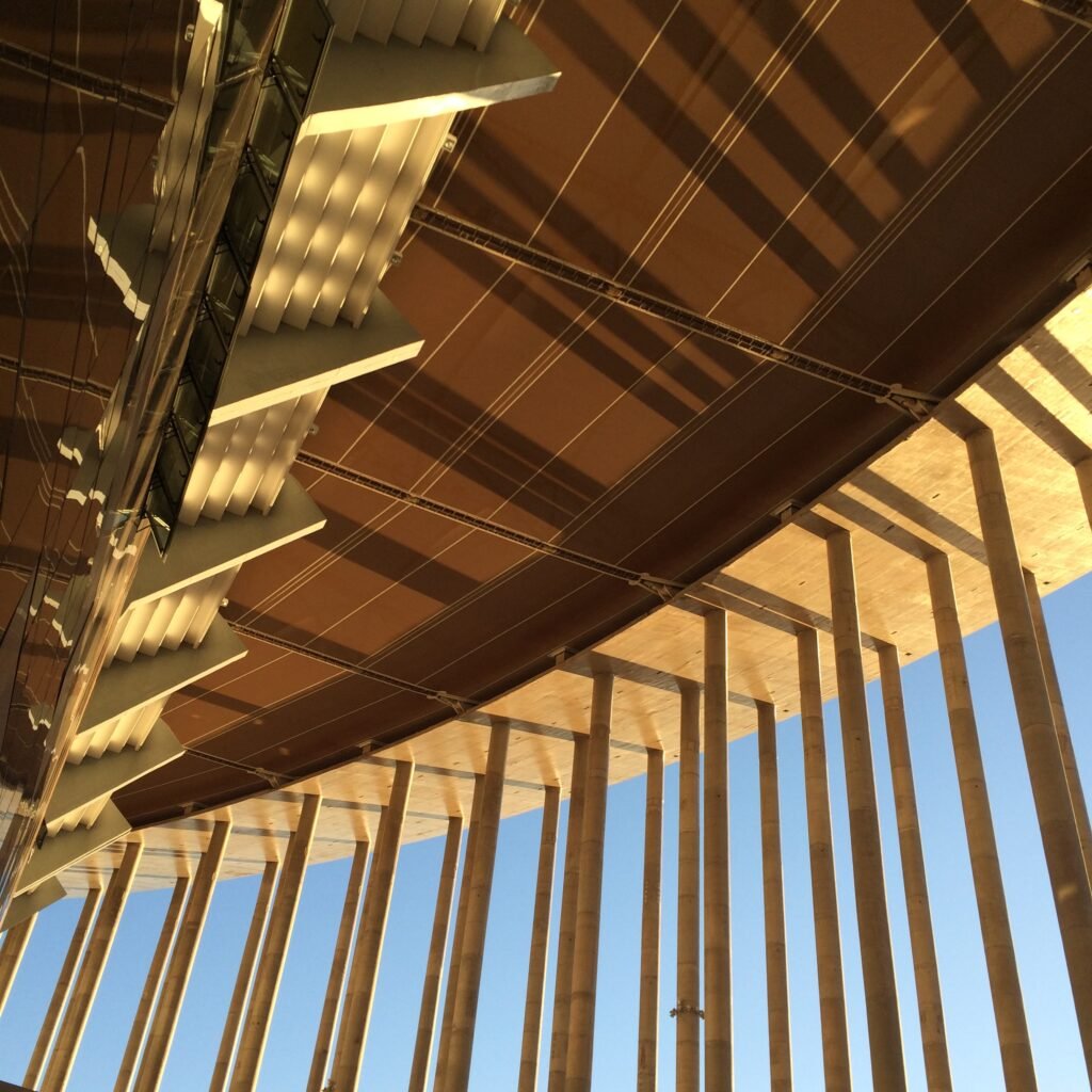 Techo de listones de madera visto desde abajo, con columnas y luz cálida
