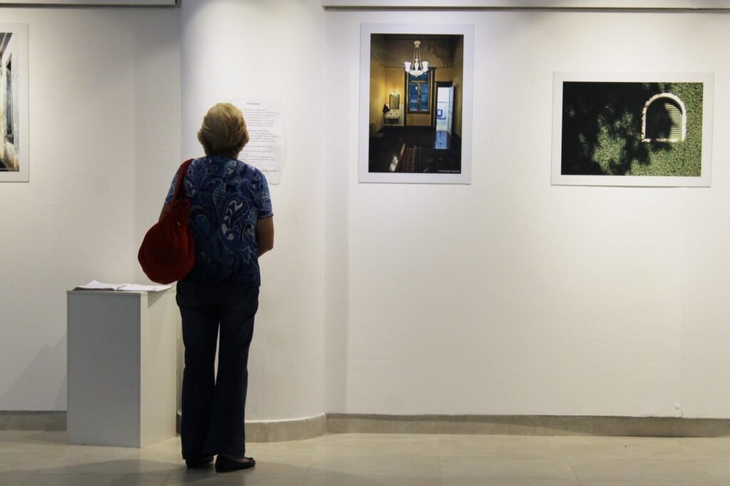 Visitante de espaldas observando fotografías en una sala de exposiciones