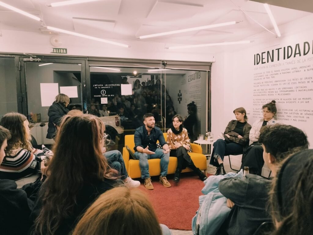 Cultura y Pensamiento Conversatorio en torno al corto Eurídice: ponentes en un sofá amarillo ante el público, en la exposición Identidades