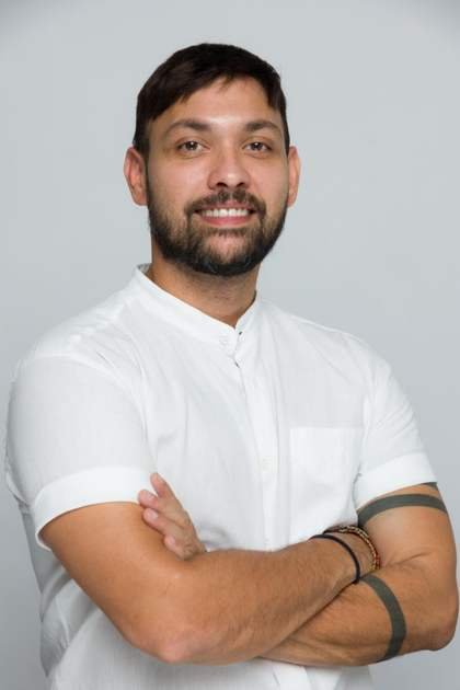 Retrato de Samuel Araújo sonriendo, con camisa blanca y los brazos cruzados